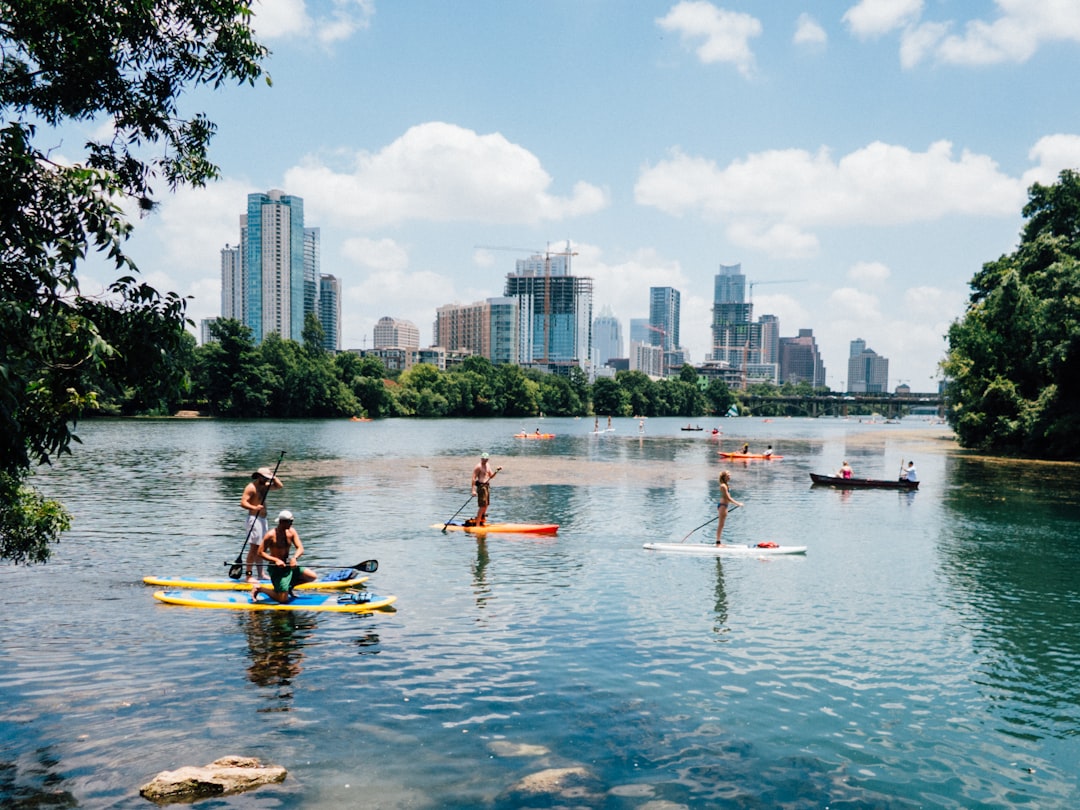People paddleboarding on calm lake water with a city skyline in the background