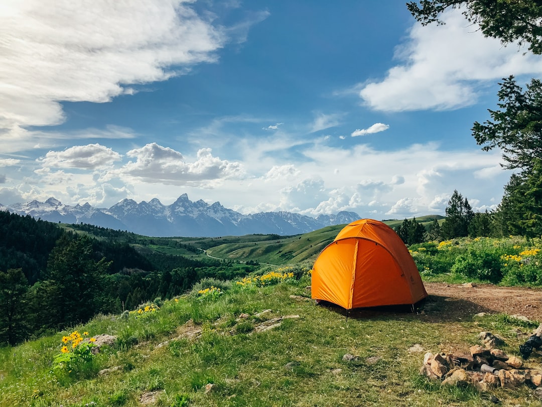 An orange tent pitched in a mountain campsite