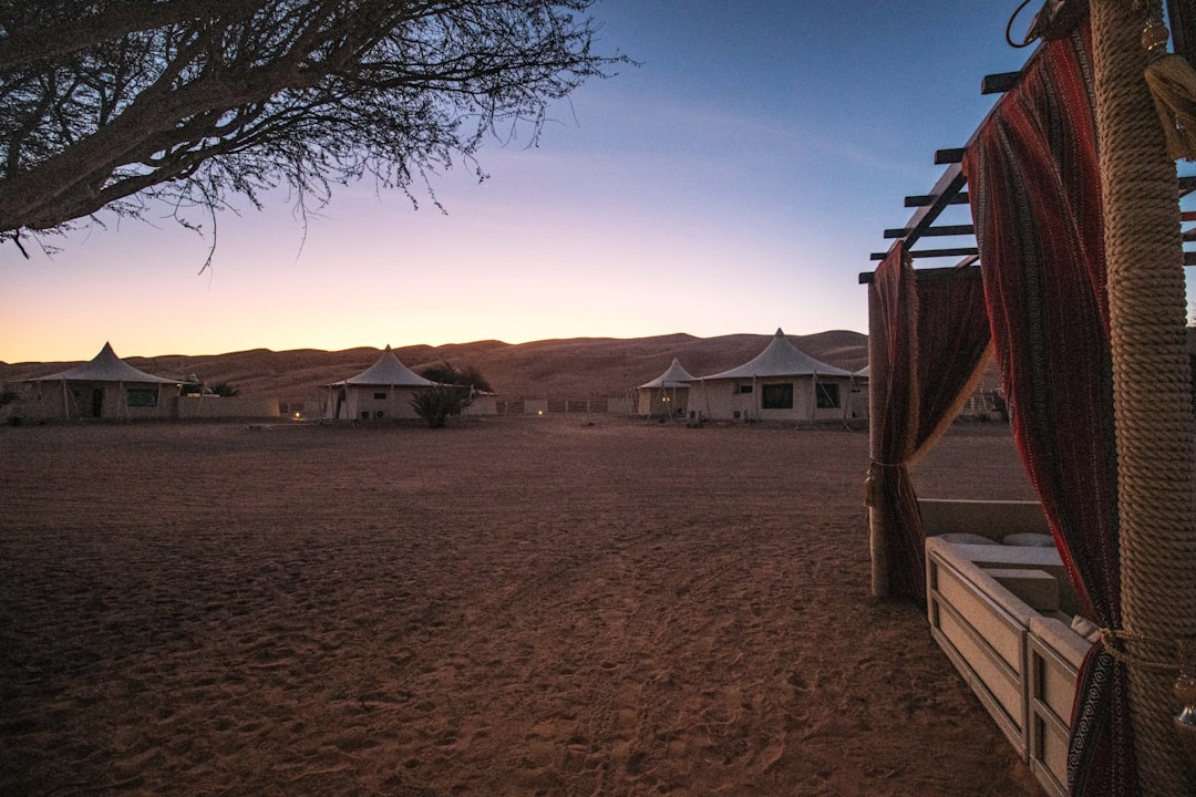 Desert glamping camp with white tents under a colorful twilight sky