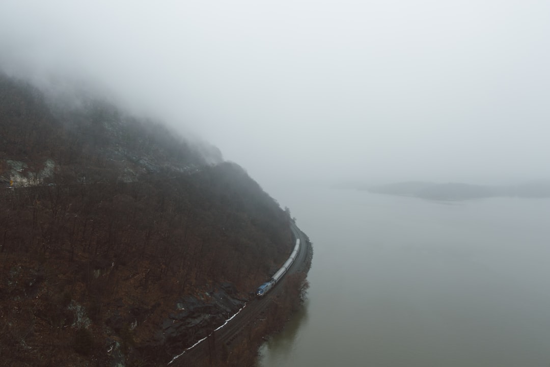 Train traveling along a misty mountain lake